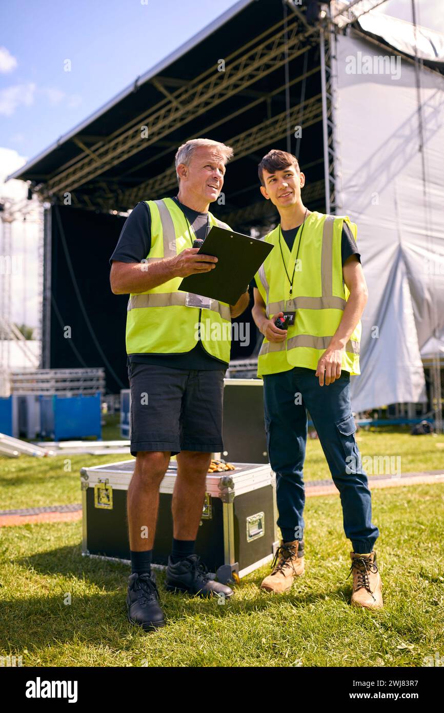 Team di produzione maschile con Flight Cases che allestiscono un palco all'aperto per il Music Festival Foto Stock