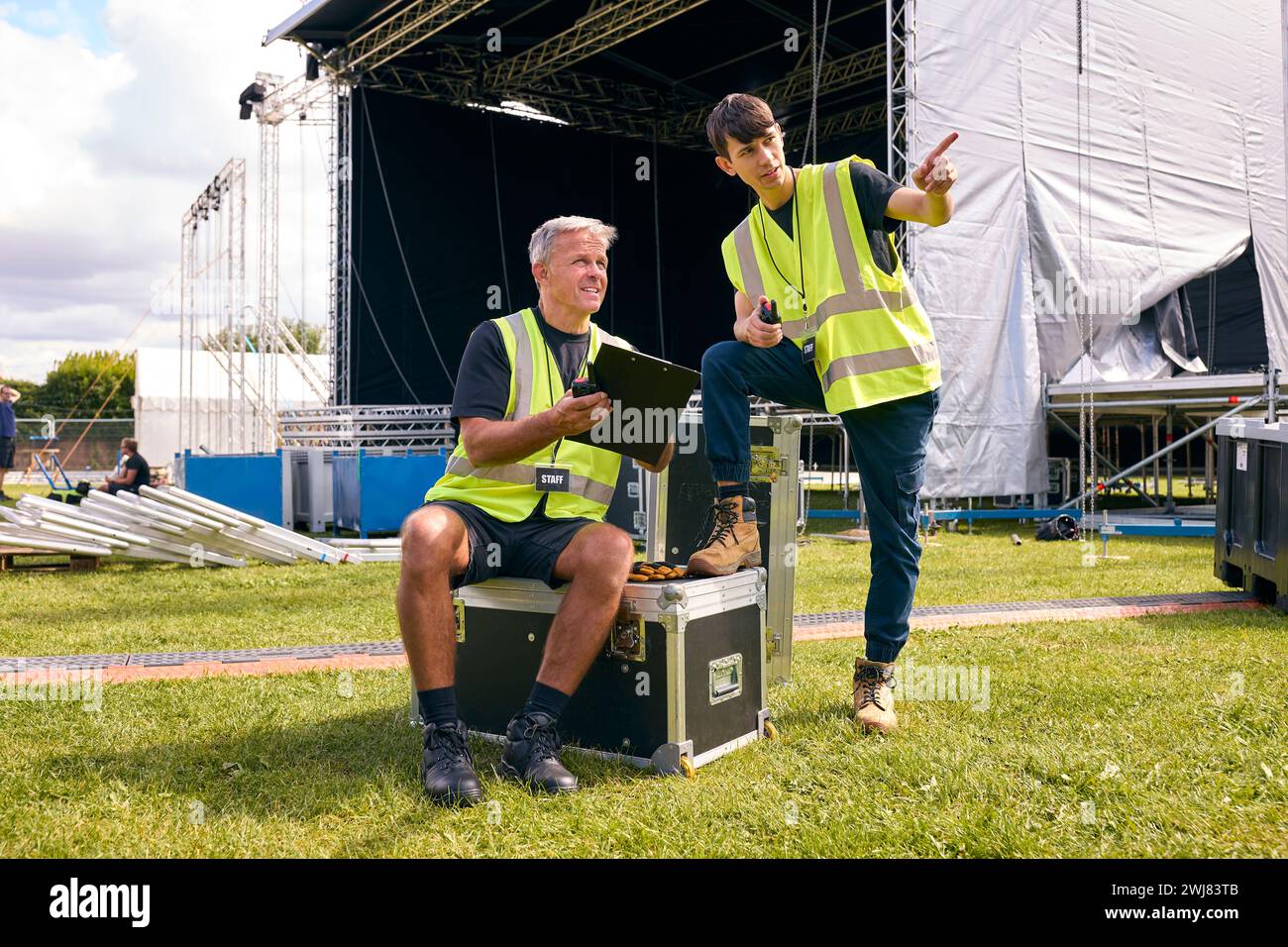 Team di produzione maschile con Flight Cases che allestiscono un palco all'aperto per il Music Festival Foto Stock