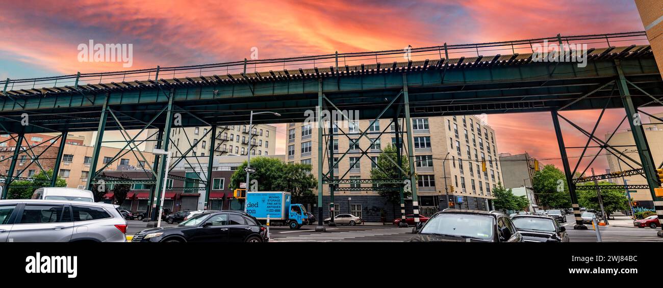 New York, USA; 3 giugno 2023: Tipici binari del treno sopraelevato e del tram del Bronx, un quartiere nella grande Mela, sotto un cielo arancione al tramonto. Foto Stock