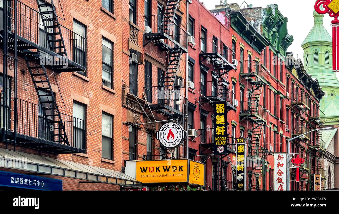 New York, USA; 4 gennaio 2024: Chinatown con marciapiedi fiancheggiati da negozi e i suoi edifici in mattoni rossi con scale di emergenza. Foto Stock