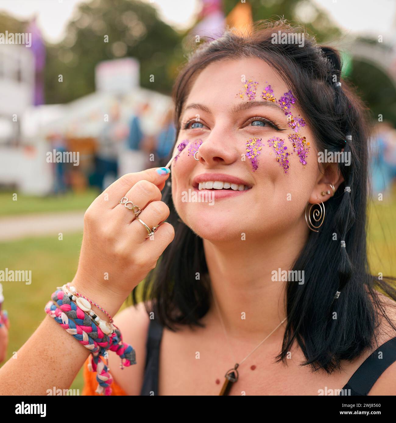 Due amiche femminili che decorano volti con glitter al Summer Music Festival Foto Stock