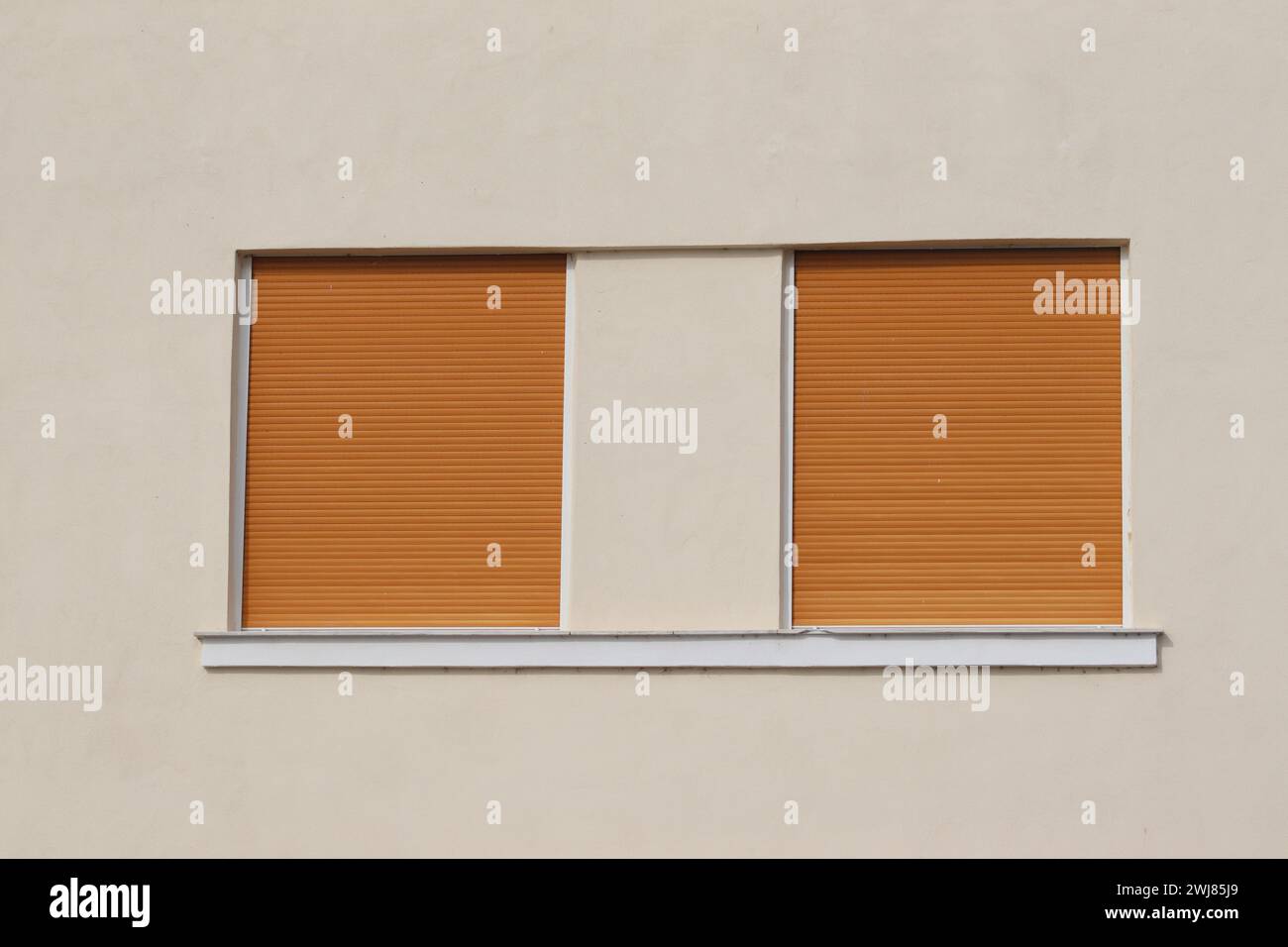 Due telai dei finestrini chiusi arancioni. Forme quadrate sulla parete beige. Salonicco Grecia 2024. Foto Stock