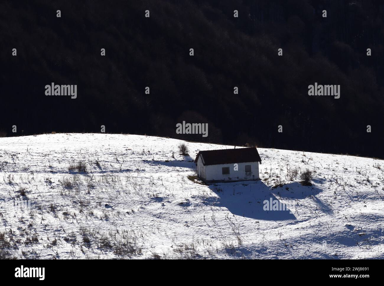 Serenità innevata. Una casa solitaria sulla montagna. Retroilluminazione illuminata. Ponikva Macedonia 2024. Foto Stock