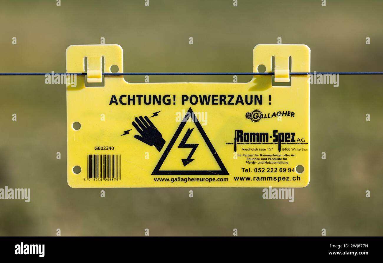 Ein Schild warnt vor einem Stromstoss bei einem elektrischen Zaun. (Laufen-Uhwiesen, Schweiz, 03.02.2024) Foto Stock