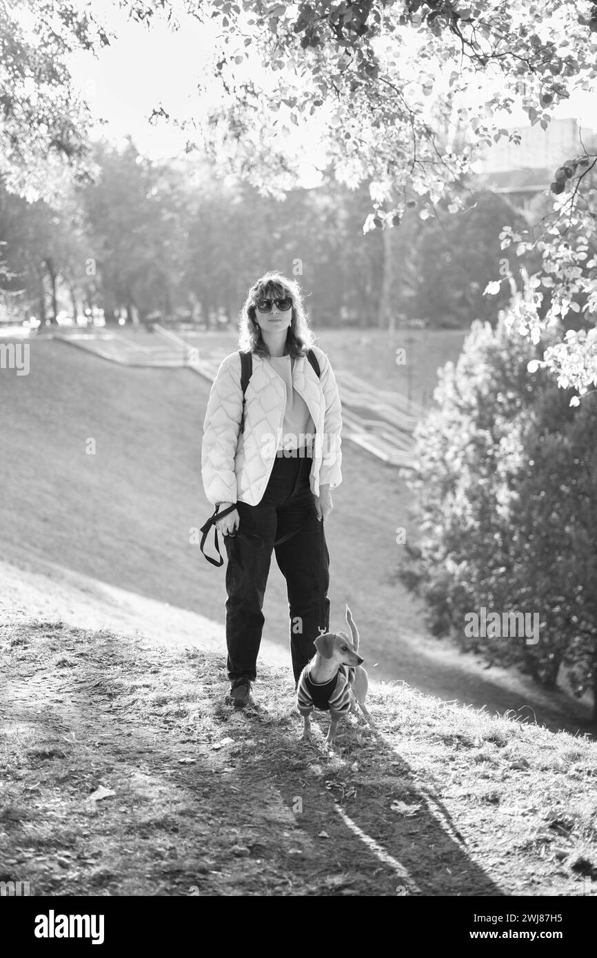 Proprietario che cammina insieme con il cane in un parco all'aperto, vacanze estive, adorabile concetto di animali domestici, amicizia tra l'uomo e il suo animale domestico. Dachshund in maglione foto di alta qualità Foto Stock