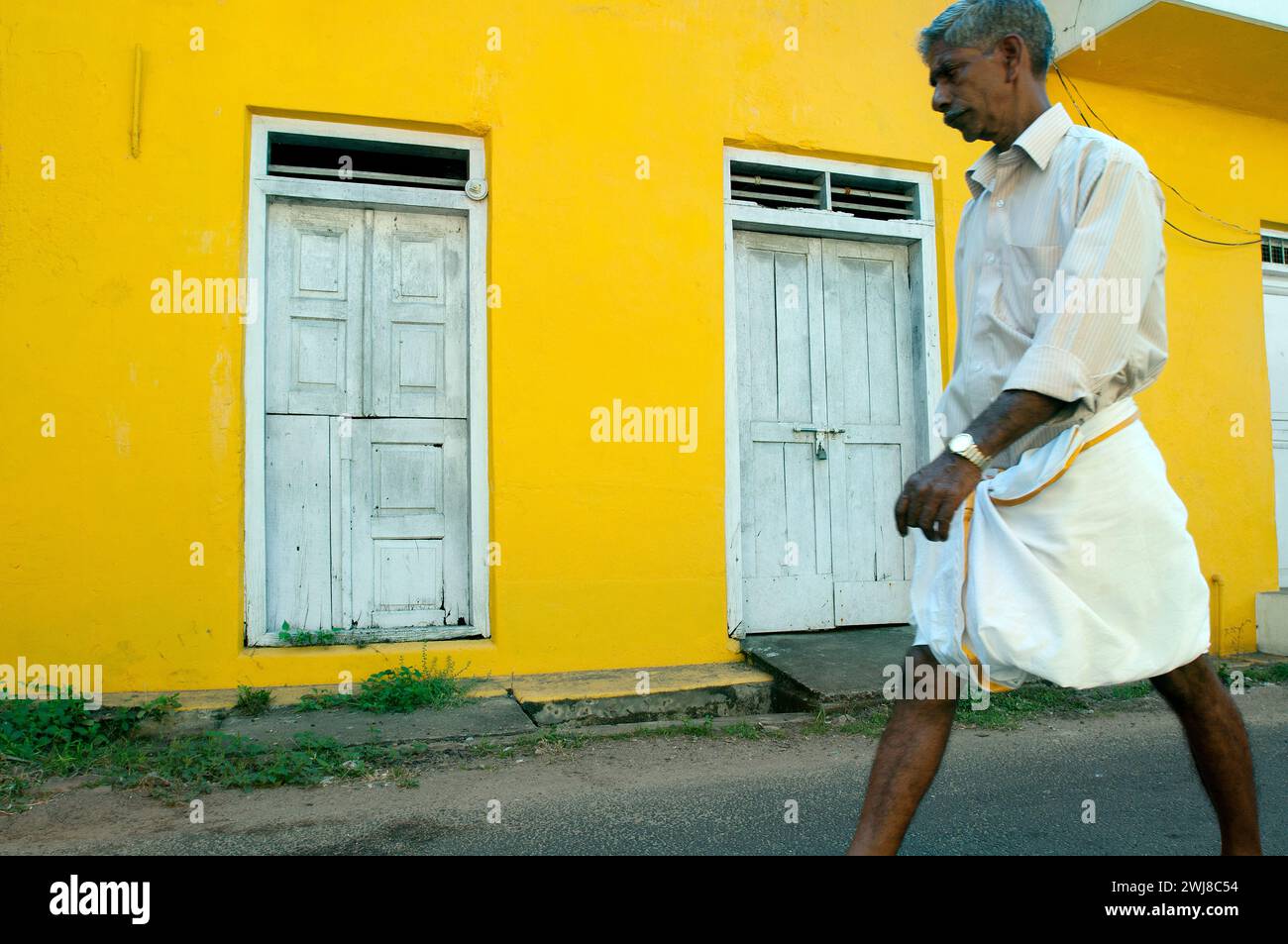Uomo che cammina, casa dipinta di giallo, Fort Cochin, Kerala, India Foto Stock