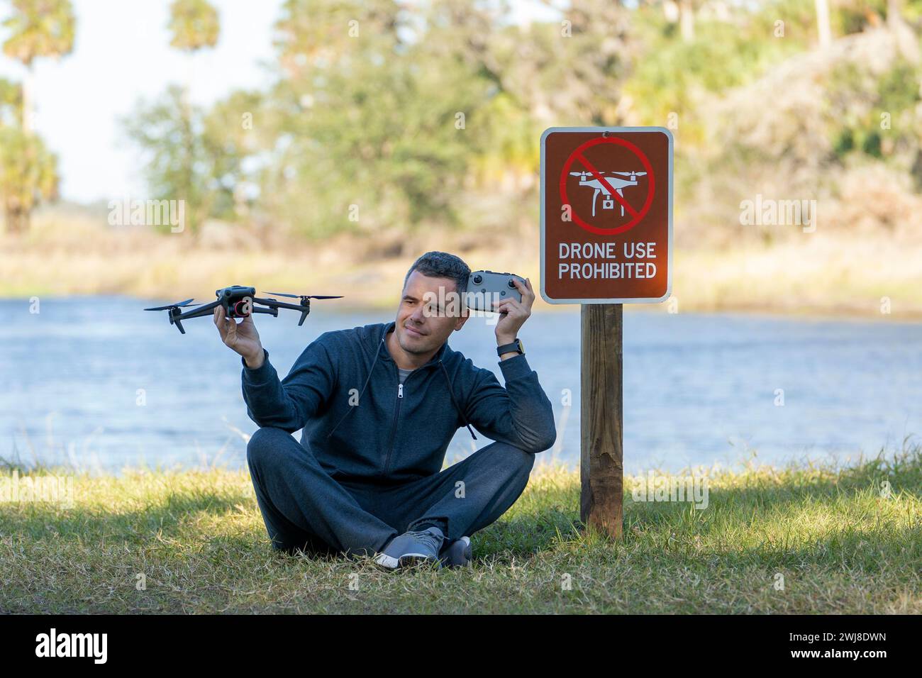 L'uomo volerà il suo quadricottero in nessuna zona di droni. L'operatore utilizza illegalmente il proprio UAS nel parco statale vicino al segnale di restrizione Foto Stock