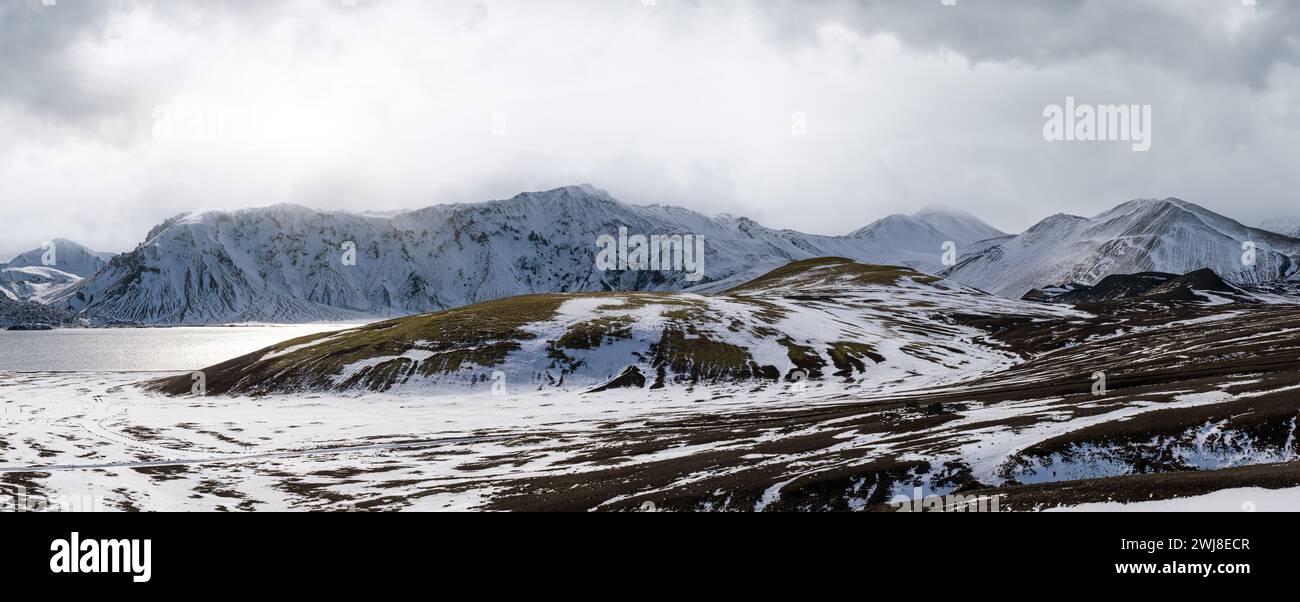 Cambiamenti di stagione negli altopiani islandesi. Montagne Landmannalaugar colorate sotto la copertura di neve in autunno. Lago Frostastadavatn ai piedi del moun Foto Stock