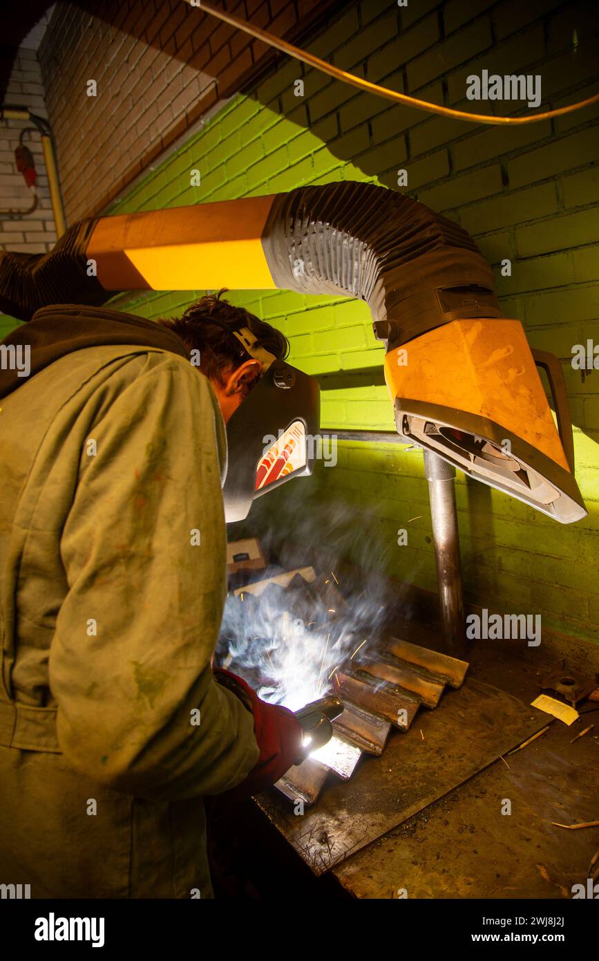 giovane uomo che salda parti metalliche Foto Stock