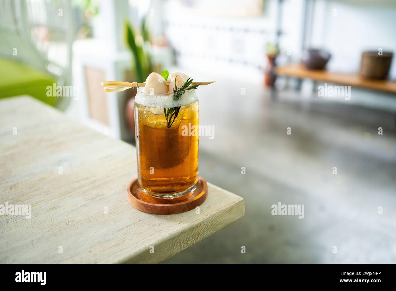 Bevanda fresca fresca di tè al lychee su un tavolo con un elegante caffè sullo sfondo. Foto Stock