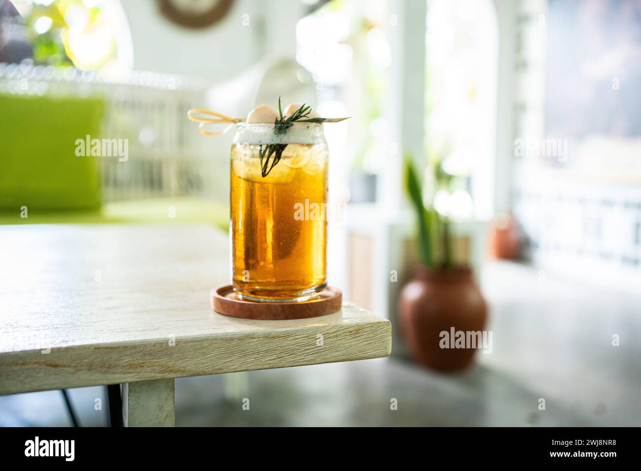 Bevanda fresca fresca di tè al lychee su un tavolo con un elegante caffè sullo sfondo. Foto Stock