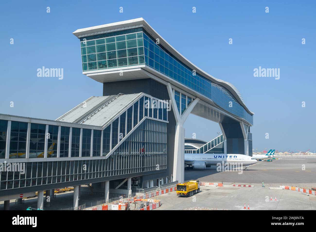 Aereo che passa sotto la piattaforma Sky Deck dell'aeroporto Chek Lap Kok, un nuovo ponte che collega i terminal dell'aeroporto di Hong Kong. Aereo sotto HKG skydeck. Foto Stock