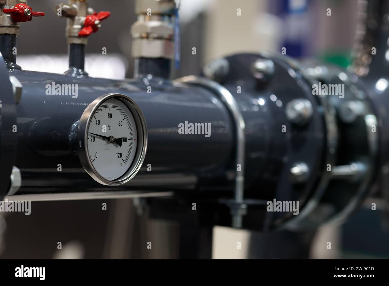 Tubo in acciaio dell'impianto di riscaldamento dell'acqua con indicatore di temperatura nel locale caldaie. Messa a fuoco selettiva. Foto Stock