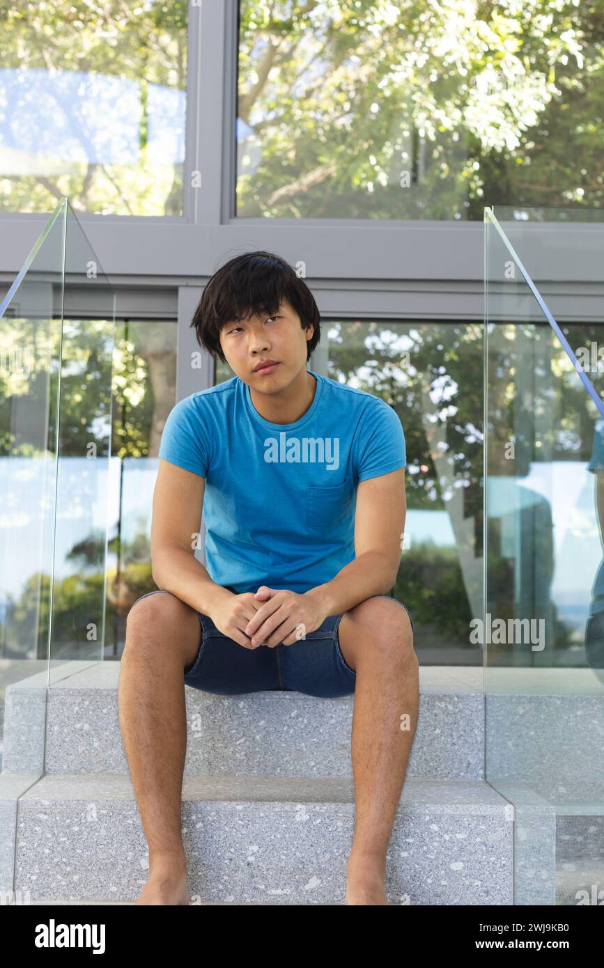 Sad adolescente asiatico ragazzo siede su gradini all'aperto, con spazio di copia Foto Stock