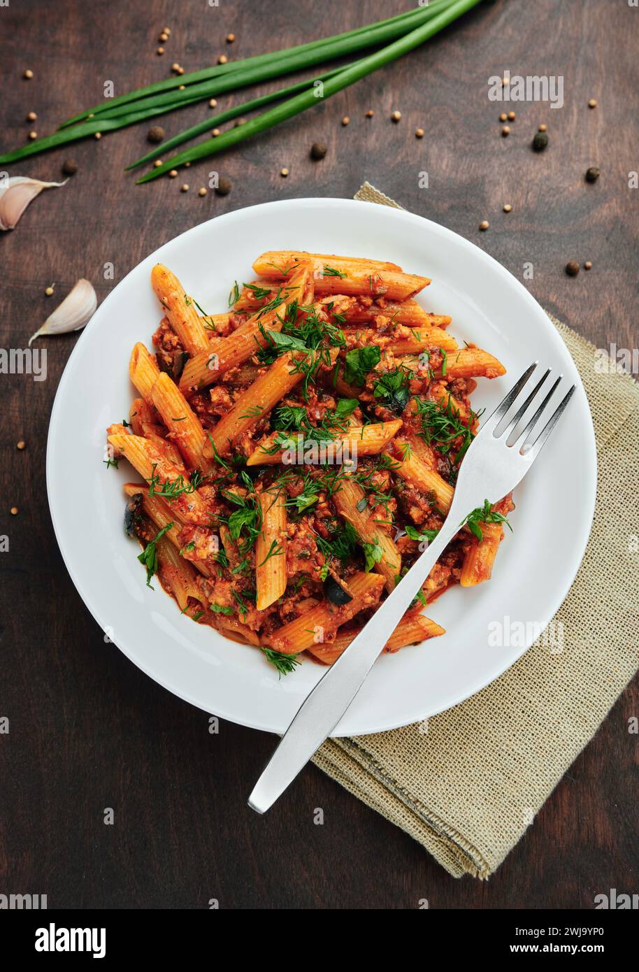 Cucina tradizionale italiana: Gustosa pasta con salsa bolognese. Deliziosi maccheroni (penne rigate) su un tavolo di legno ruvido. Vista dall'alto Foto Stock