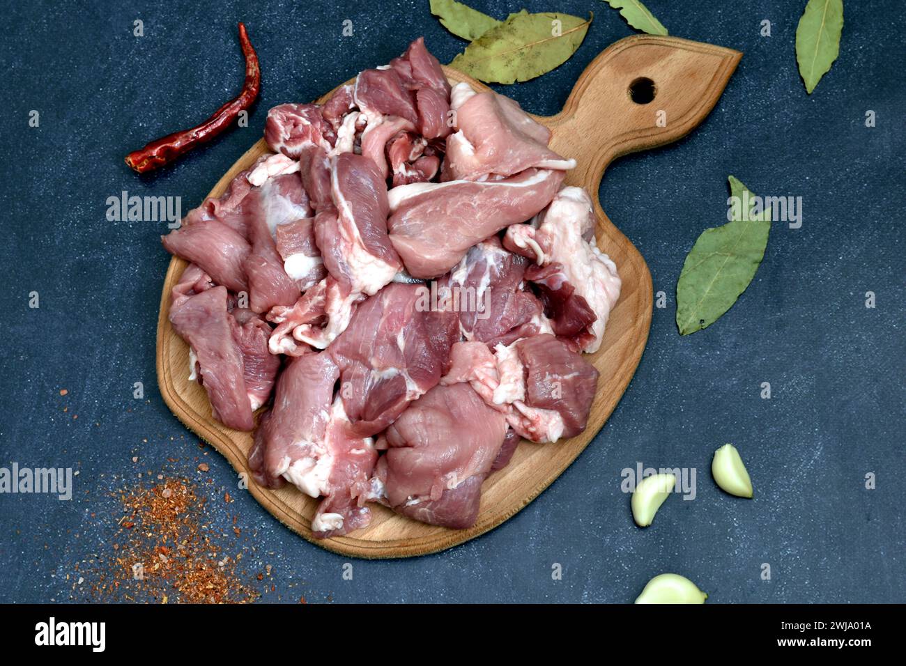 La carne di maiale tagliata a pezzi si trova su un tagliere, vista dall'alto. Foto Stock