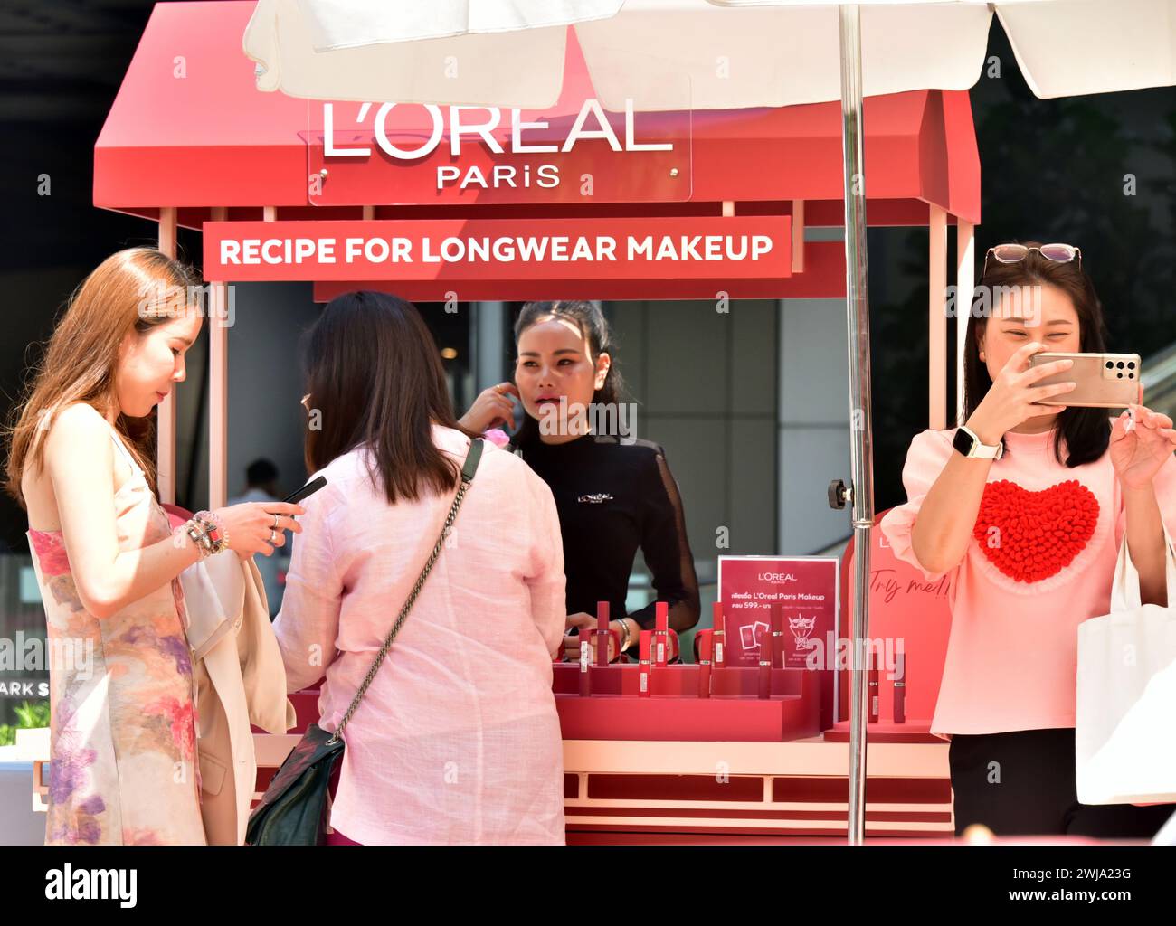 Promozione del marchio l'Oréal per san valentino 2024 nel centro di Bangkok, Thailandia, Sud Est Asiatico, le giovani donne guardano alla stalla del trucco Foto Stock