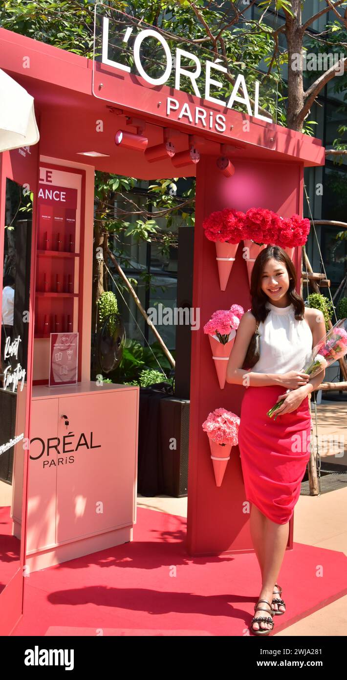 Promozione marchio l'Oréal per san valentino 2024 nel centro di Bangkok, Thailandia, Sud Est Asiatico, giovane donna posa con fiore davanti a una stalla Foto Stock