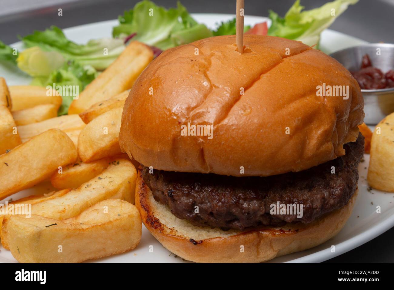 Beefburger in panino con patatine fritte Foto Stock