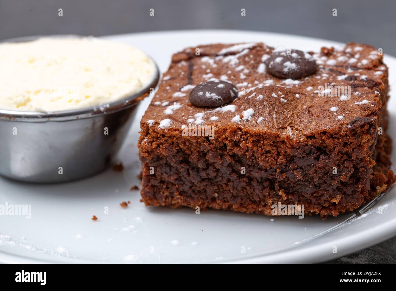 Brownie al cioccolato con una pentola di panna Foto Stock