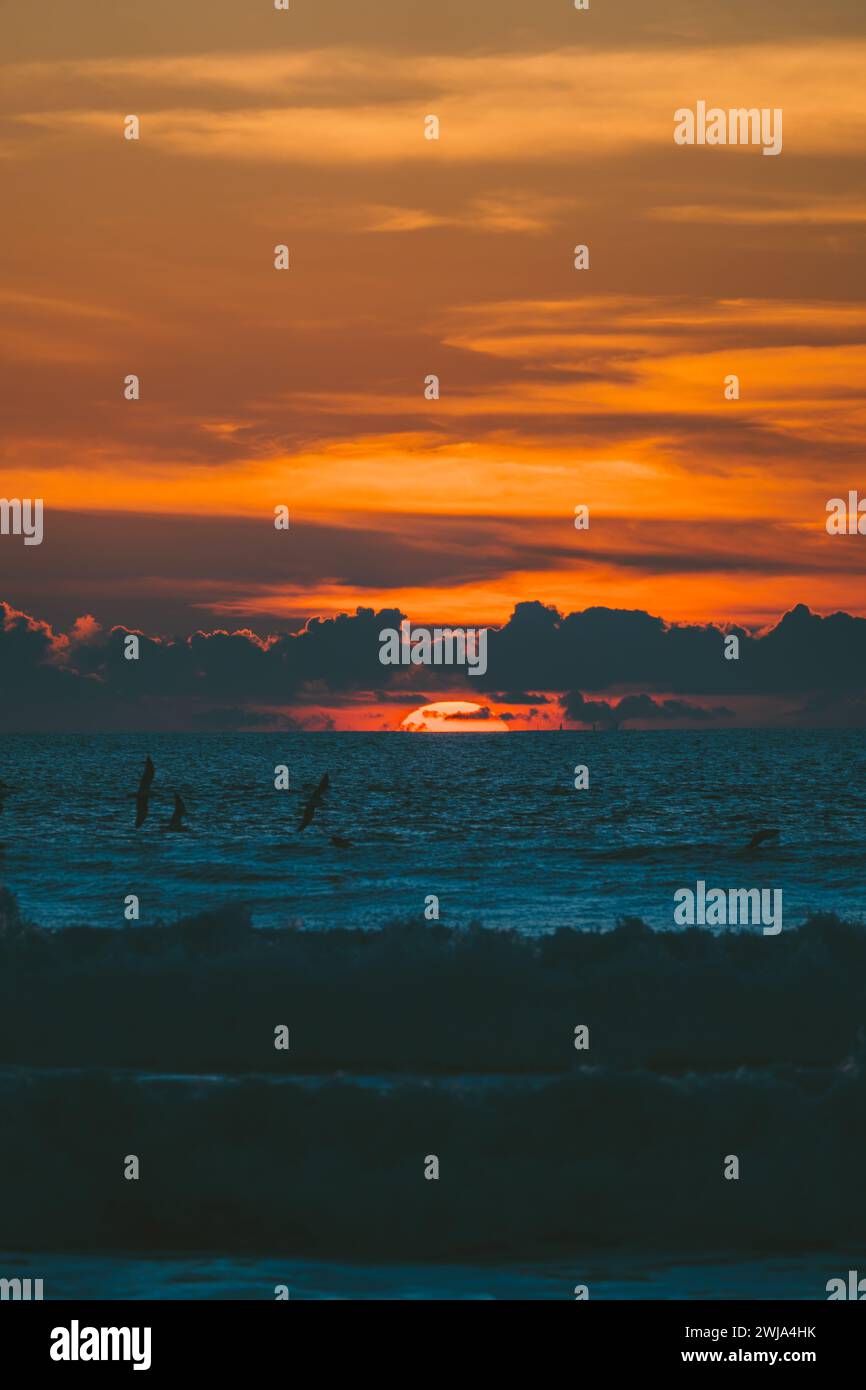 Vista pittoresca di un tramonto colorato con un cielo arancione nuvoloso con gabbiani sopra il mare ondulato nel tardo pomeriggio nella natura, in campagna Foto Stock