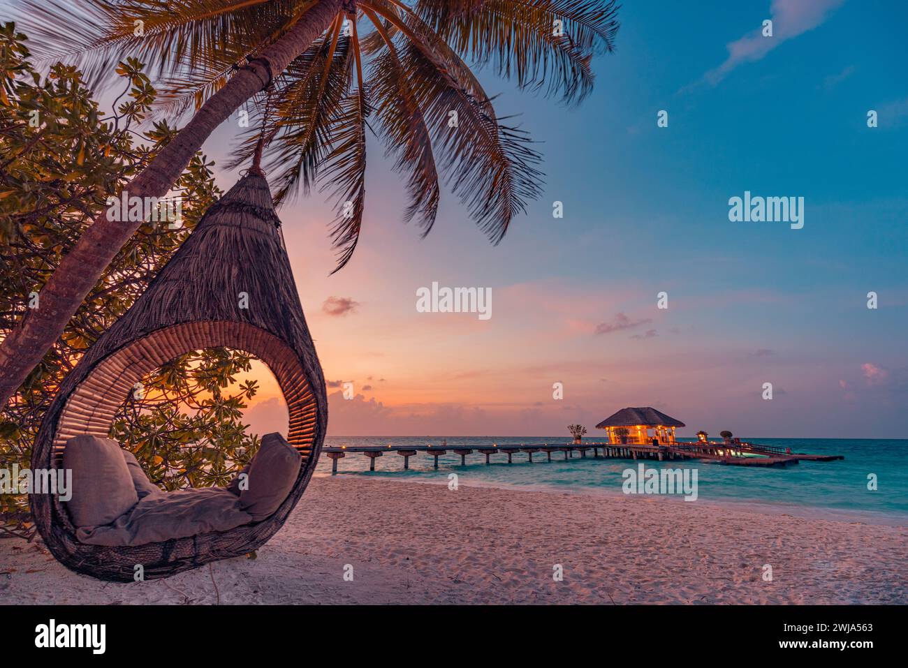 Tramonto tropicale sullo sfondo della spiaggia, paesaggio estivo dell'isola con altalena o sabbia amaca romantica spiaggia di mare. Bellissima vacanza turistica sulla spiaggia Foto Stock