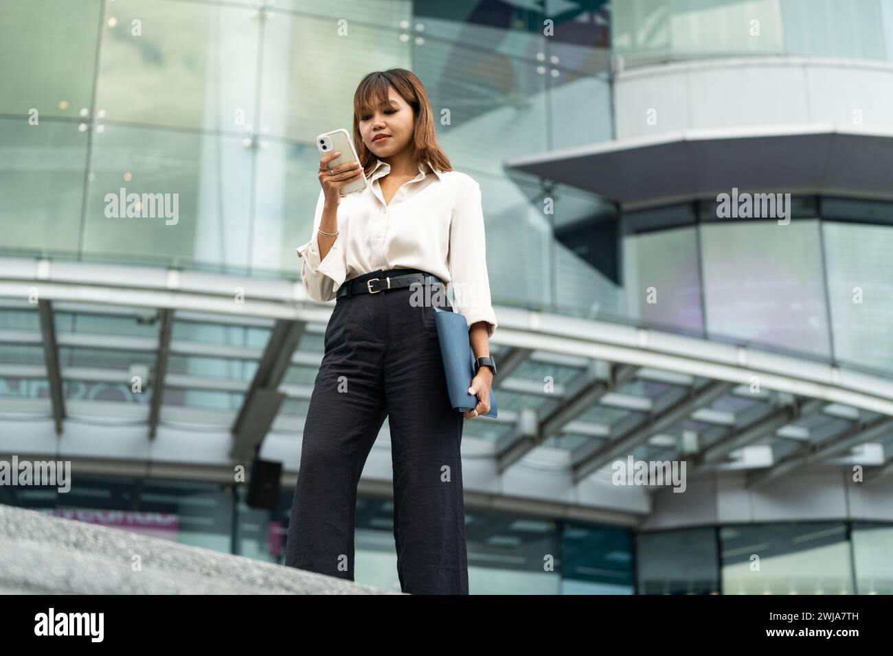 Da sotto una donna d'affari thailandese controlla il suo telefono nel vivace paesaggio urbano di Chiang mai. Foto Stock