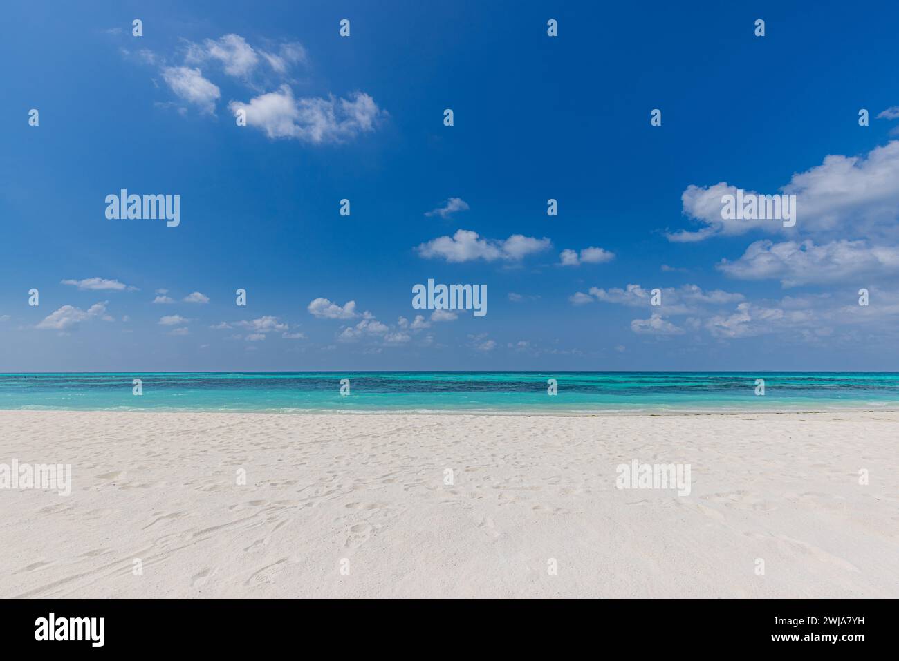 Vista sulla spiaggia tropicale. Tranquilla e rilassante spiaggia mediterranea, cielo azzurro e soleggiato e sabbia bianca. Costa tranquilla e idilliaca Foto Stock