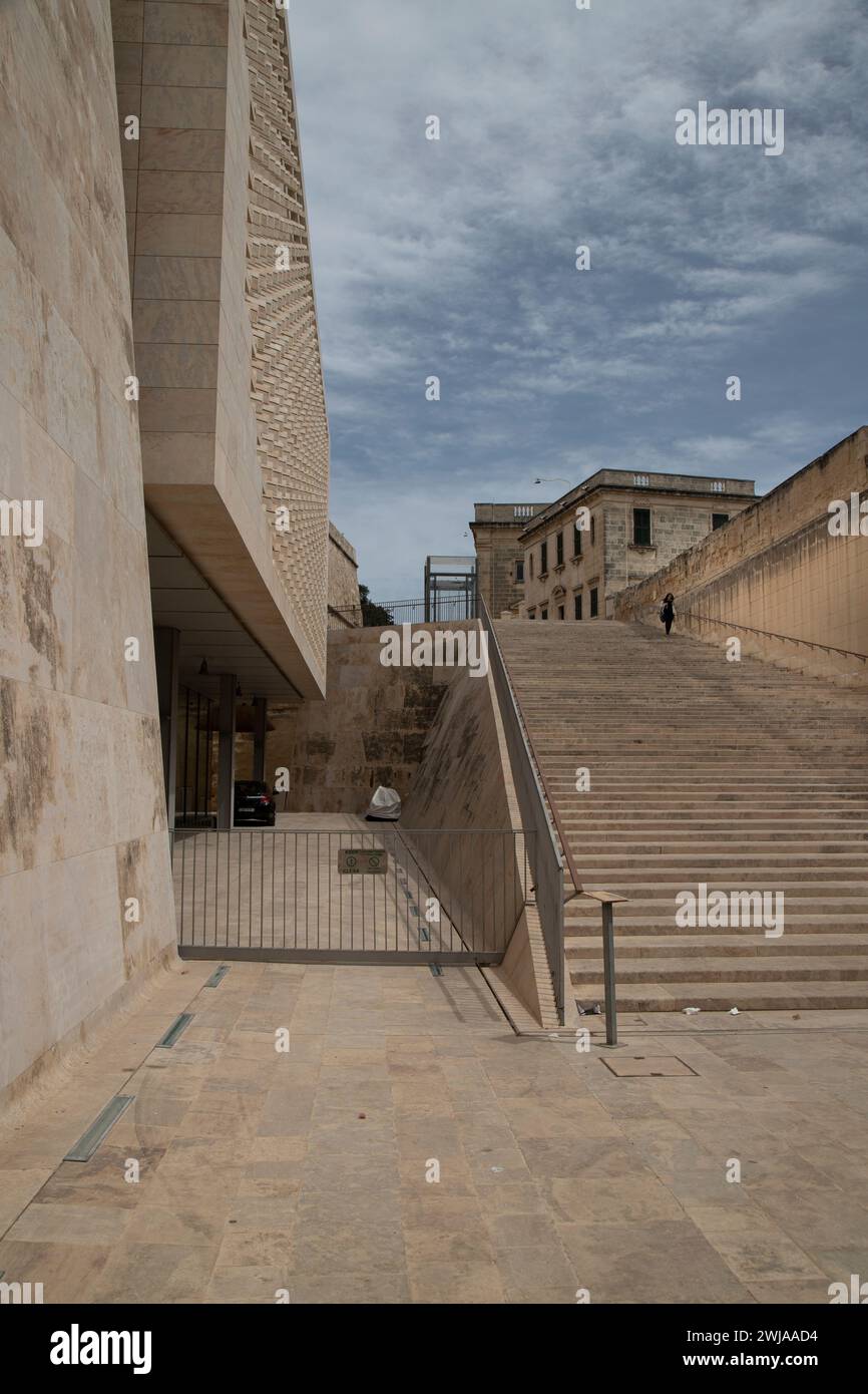 Una donna che scende gradini vicino a un grande edificio a la Valletta, Malta Foto Stock