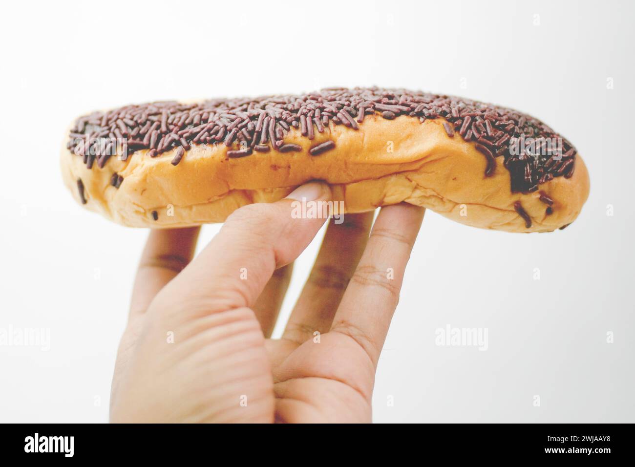 Primo piano che tiene il pane con degli spruzzi di cioccolato che coprono il meses isolato su sfondo bianco Foto Stock