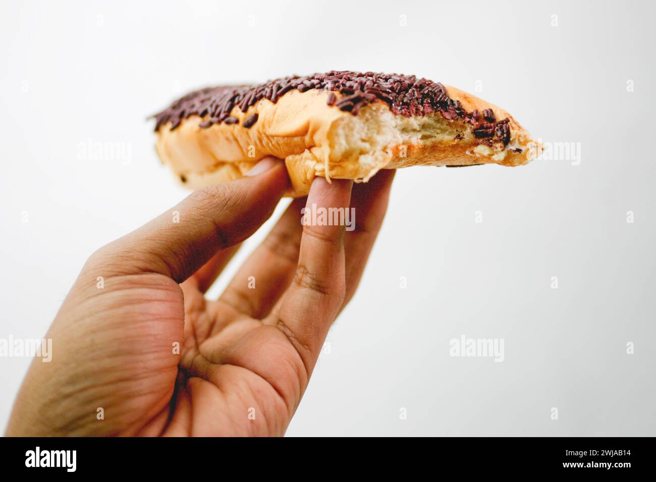 Primo piano che tiene il pane con degli spruzzi di cioccolato che coprono il meses isolato su sfondo bianco Foto Stock
