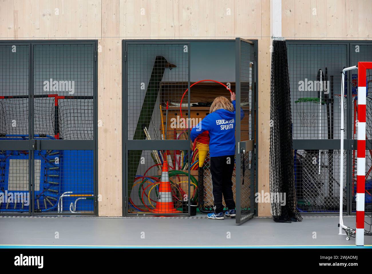 Donna, allenatrice sportiva in un complesso sportivo. Qui, prepariamo un evento sportivo, mettiamo via le attrezzature Foto Stock