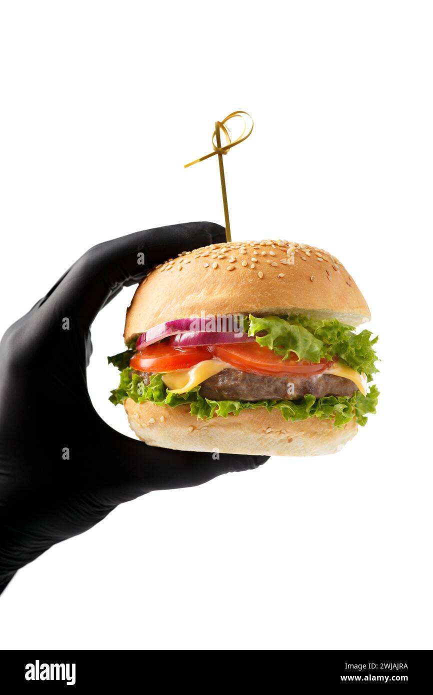 Una mano con un guanto nero contiene un succulento e appetitoso hamburger di manzo su sfondo bianco. Hamburger in mani isolate. Banner, pubblicità sui fast food. Foto Stock