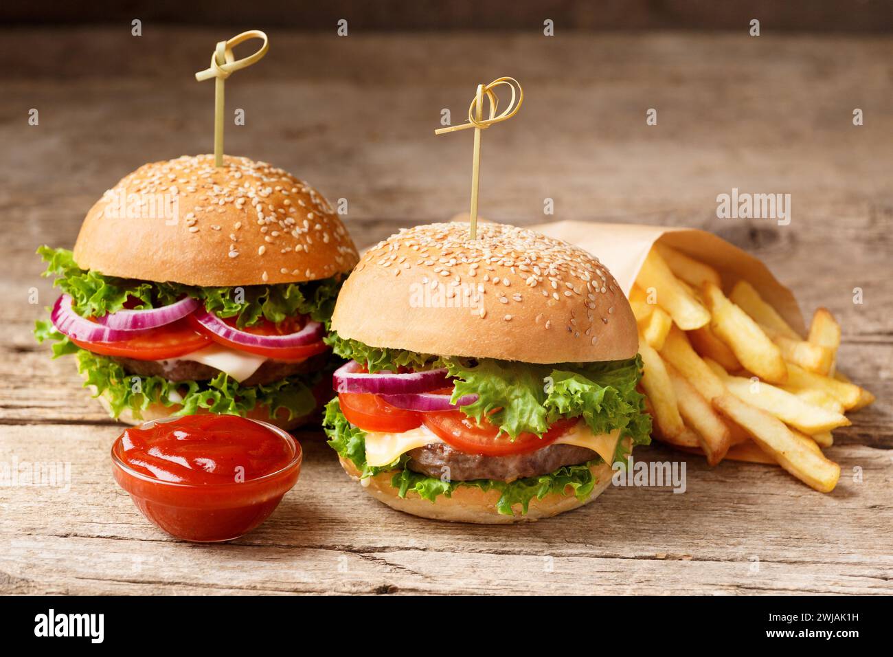 Due hamburger, patatine fritte e salse su uno sfondo rustico di legno. Fast food, hamburger fatti in casa Foto Stock
