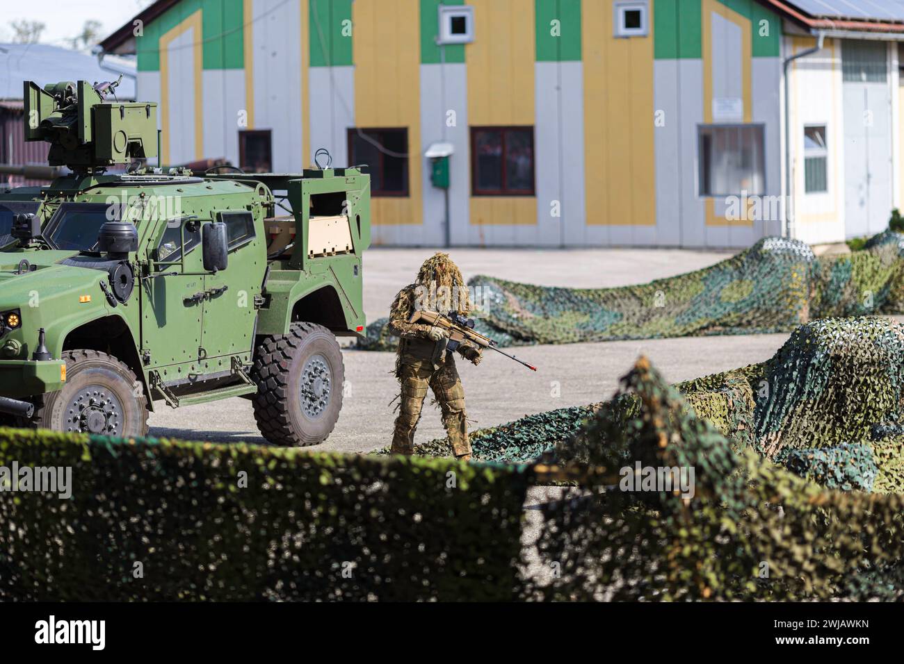 Un soldato in abiti mimetici e un veicolo militare corazzato verde a uno spettacolo Foto Stock