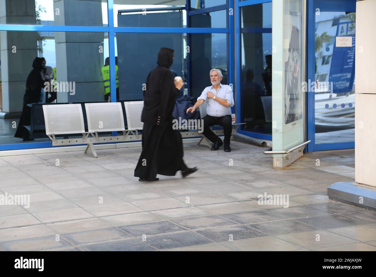 Atene Grecia Aeroporto Internazionale di Atene (AIA) Eleftherios Venizelos donna che indossa nero e porta una tazza di caffè all'esterno del terminal Foto Stock