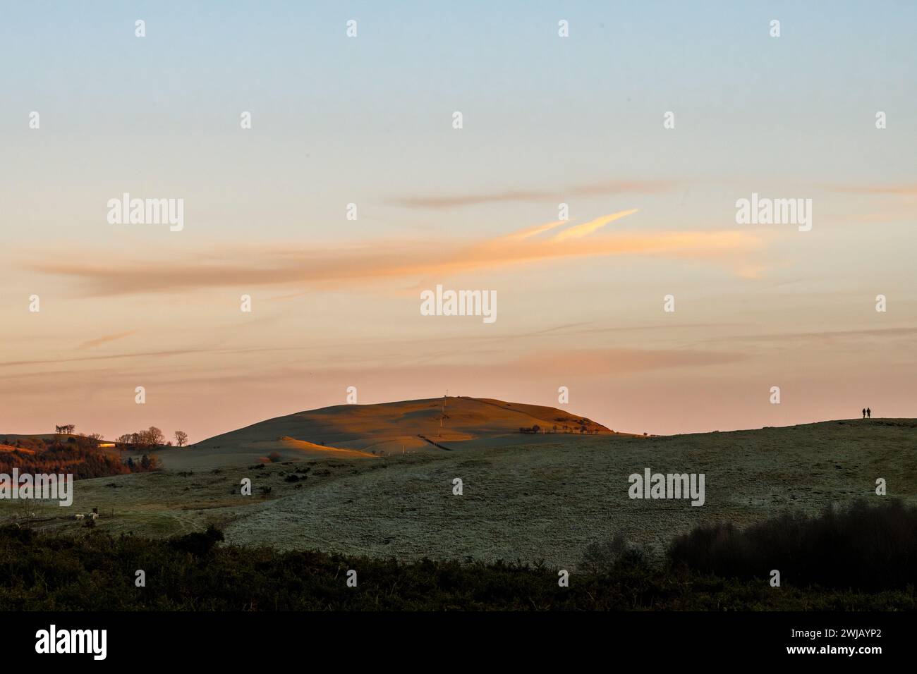 Due persone guardano il tramonto durante una passeggiata serale invernale nella campagna di confine gallese a Llandegley, vicino a Llandrindod Wells, Powys, Regno Unito Foto Stock
