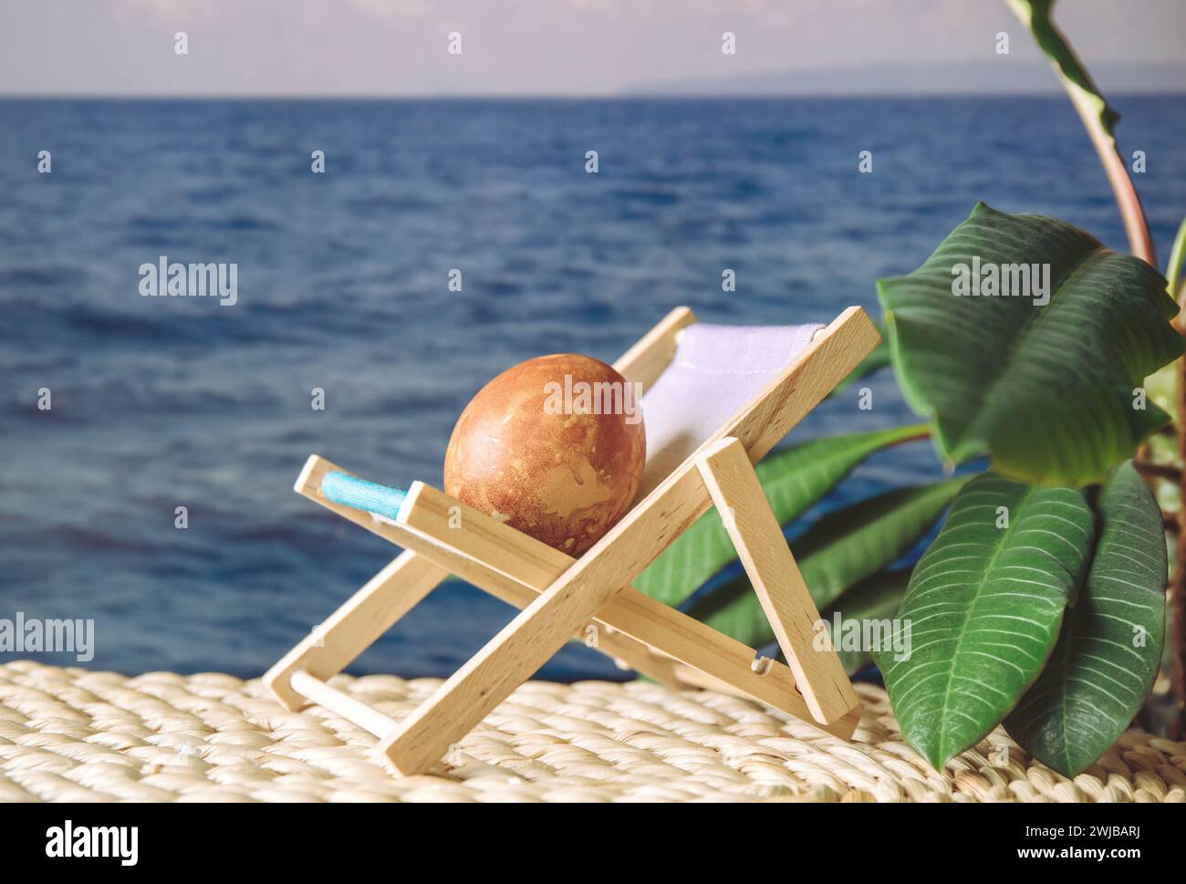 Uovo di Pasqua in una vacanza al mare soleggiata sedetevi sul lettino prendisole, concetto di vacanza di Pasqua. Foto Stock