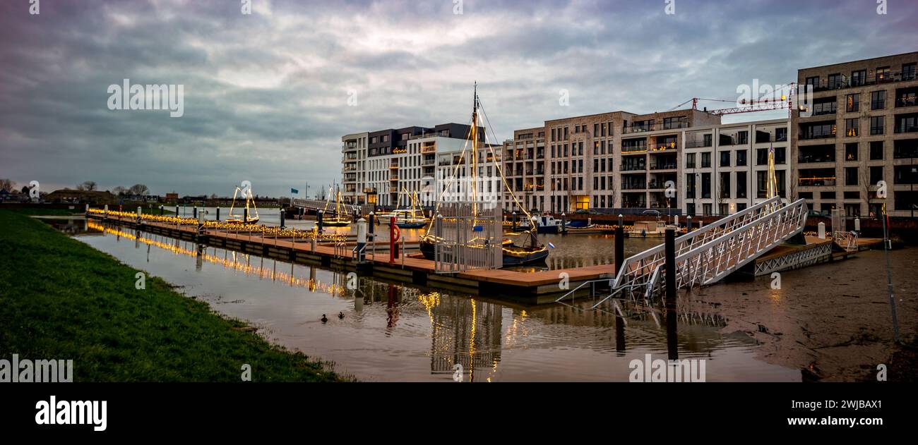 Alto livello dell'acqua del fiume IJssel con riflesso di barche da diporto nel porto di Noorderhaven con luci di vacanza intorno alla banchina in primo piano Foto Stock