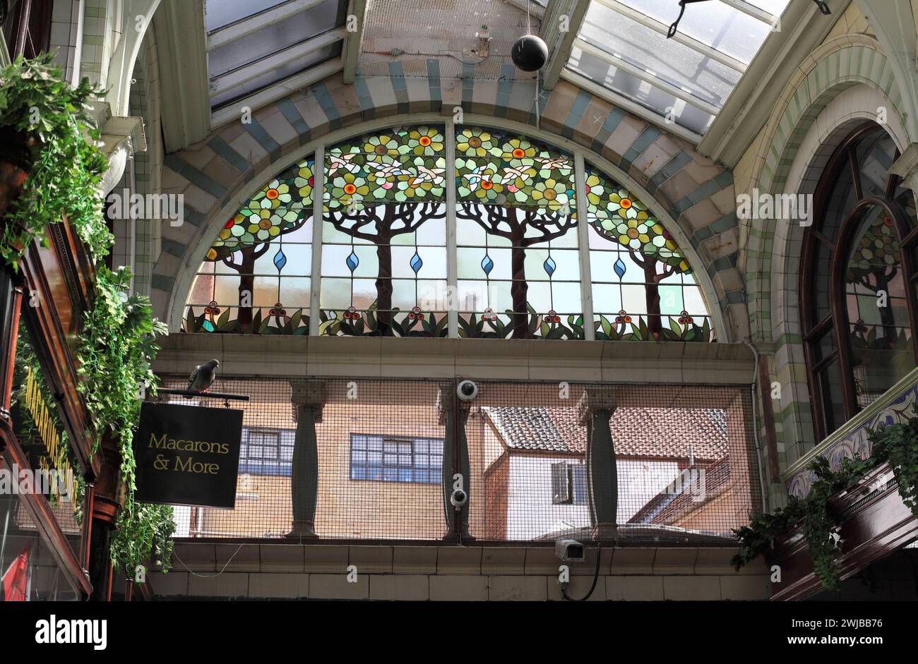 Vetrata semicircolare raffigurante alberi, fiori e uccelli sopra l'ingresso est della Royal Arcade di Norwich. Foto Stock