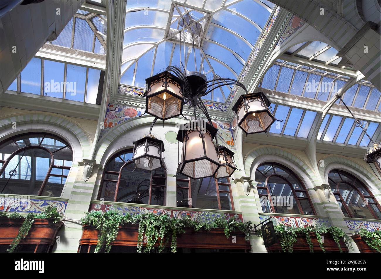 Guardando in alto i paralumi in stile art nouveau appesi al tetto in vetro e legno della Royal Arcade di Norwich. Foto Stock