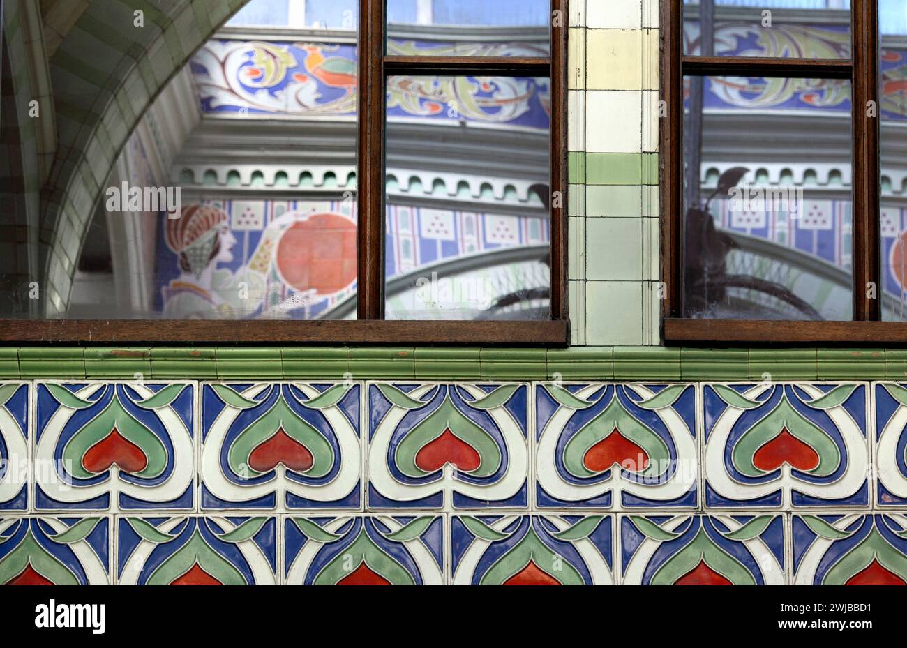 Primo piano della decorazione art nouveau all'interno della Royal Arcade di Norwich. Le finestre a specchio riflettono più disegni sulla parete opposta. Foto Stock