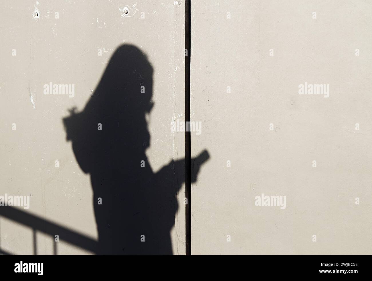 Ombra di Una donna che usa e guarda Un telefono cellulare, Londra Regno Unito Foto Stock