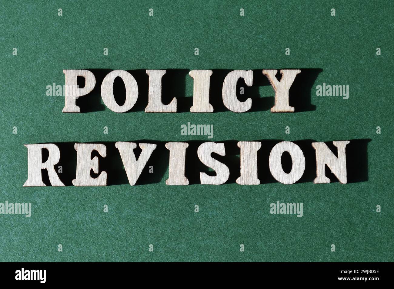 Revisione della politica, parole in alfabeto di legno isolate su sfondo verde come titolo del banner Foto Stock