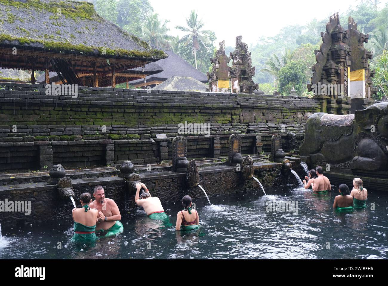 Gli occidentali eseguono un rituale di purificazione nel tempio Tirta Empul vicino a Ubud a Bali, Indonesia Foto Stock