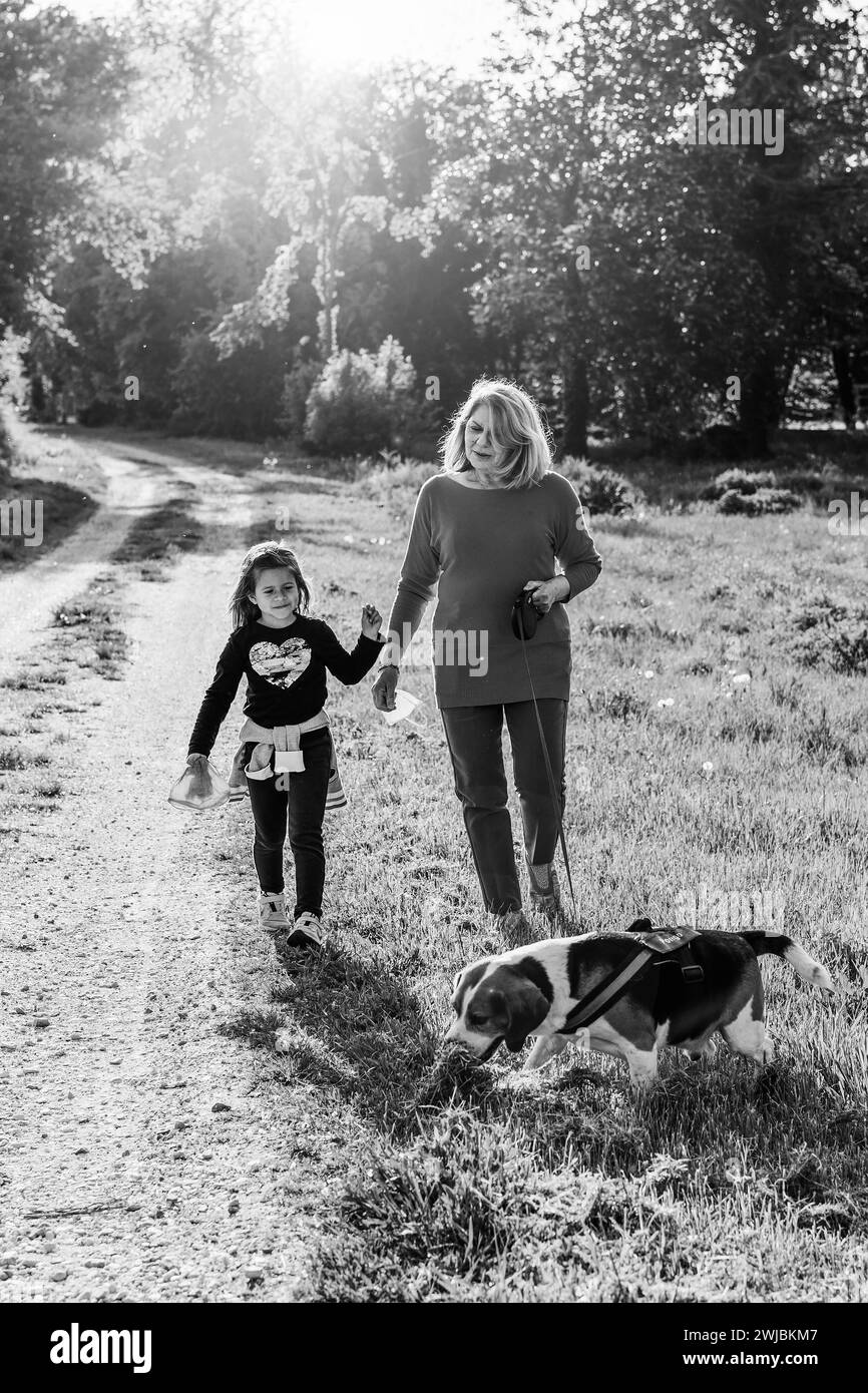 Donna anziana alla moda e la sua bambina godendo una passeggiata in campagna con il loro cane beagle - nonna e nipote felici insieme Foto Stock