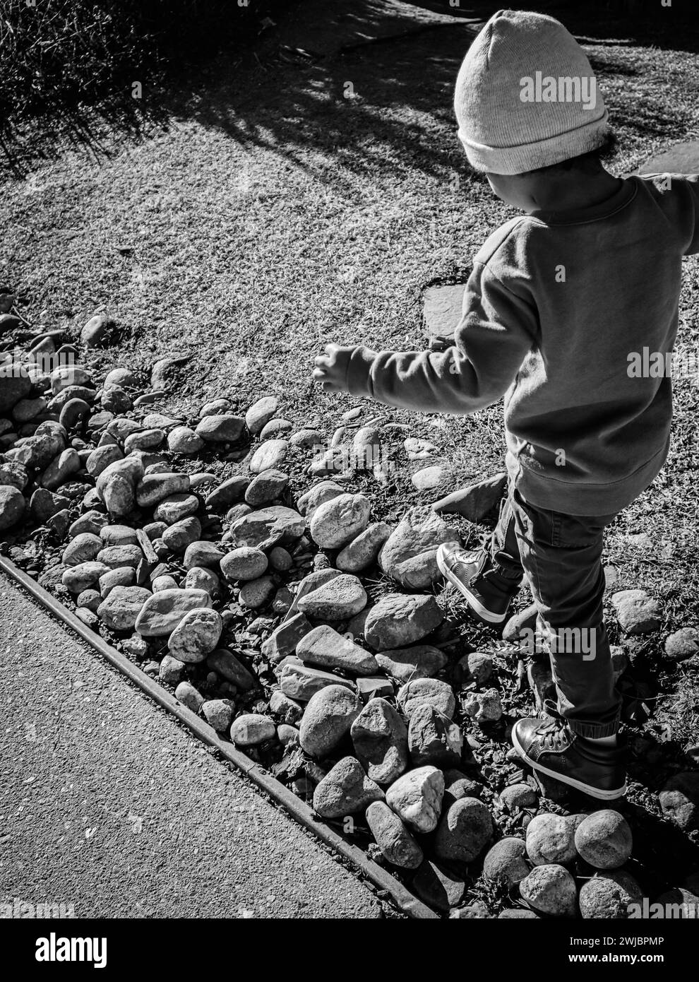 Immagine in bianco e nero di un bambino che esplora con gioia un giardino roccioso Foto Stock