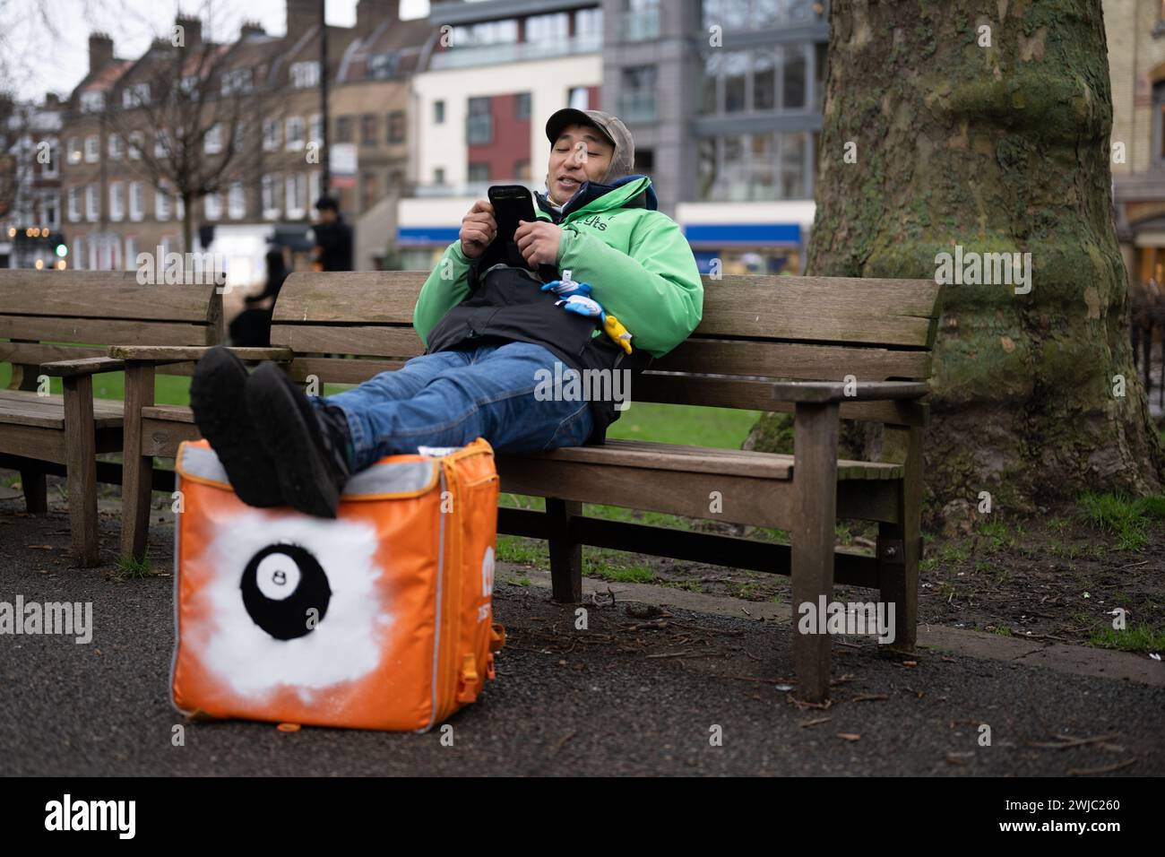 14 febbraio 2024: Un corriere Uber Eats si prende una pausa tra un lavoro e l'altro a Islington Green, Londra. I corrieri Deliveroo e Uber Eats colpiscono stasera tra le cinque e le dieci per garantire condizioni di lavoro migliori e pagare. Foto Stock