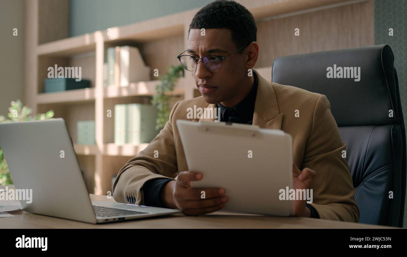 Uomo d'affari contabile afroamericano lavoratore d'ufficio maschile scrivere dati finanziari piano di analisi strategia uomo d'affari concentrato lavorare con computer portatile Foto Stock