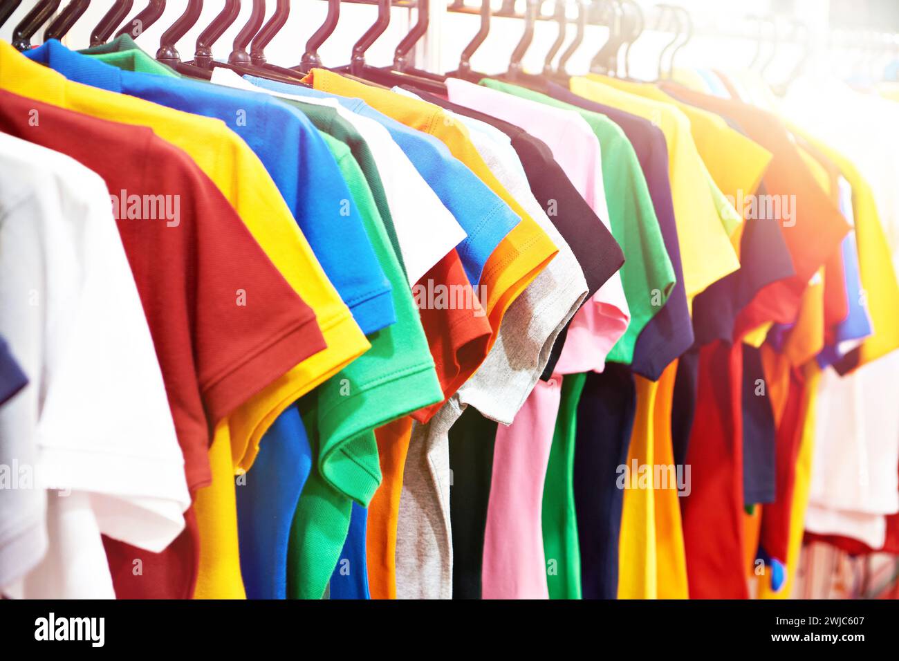 T-shirt colorate alla moda su un appendiabiti in un punto vendita Foto Stock